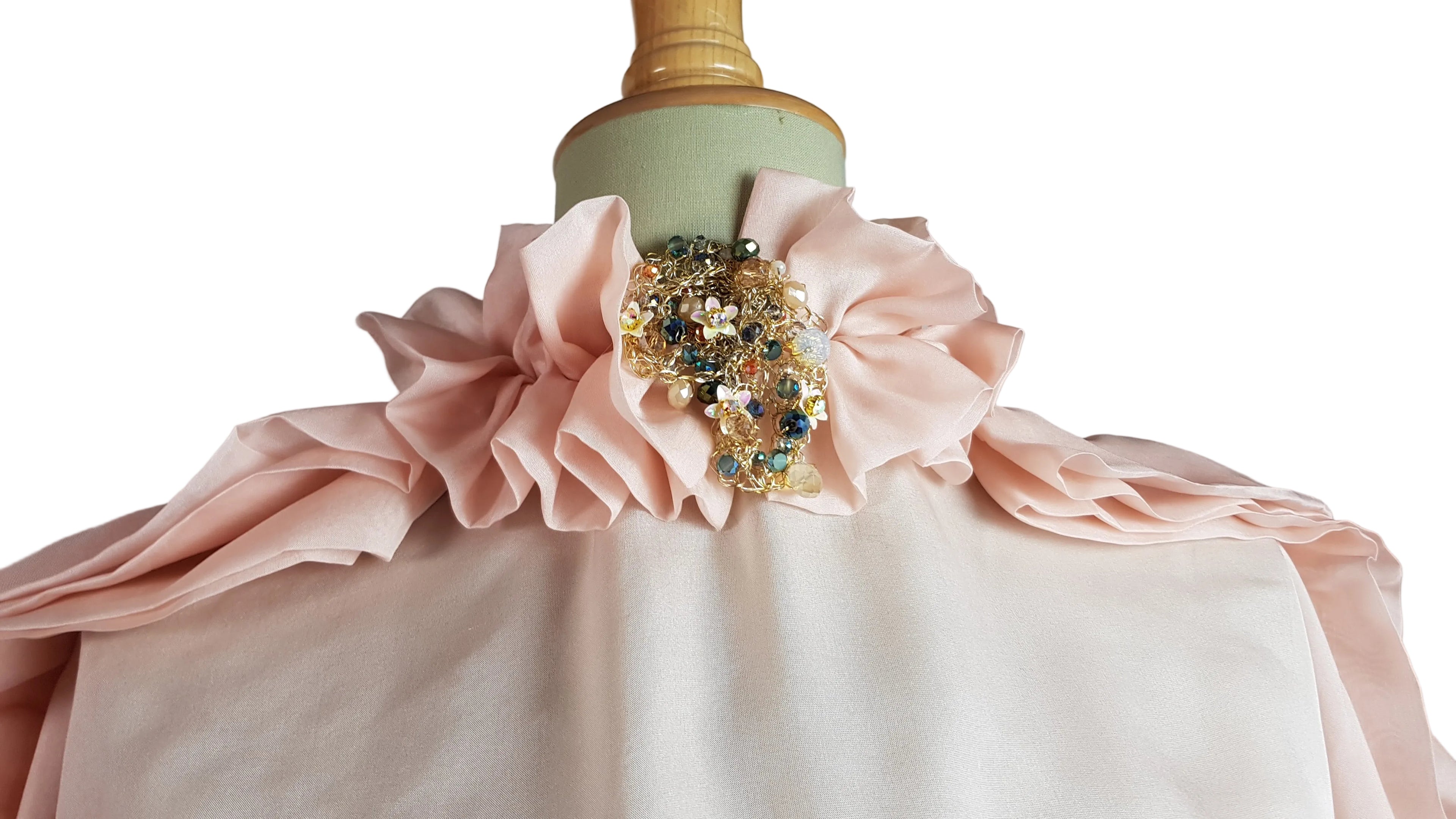 Mannequin wearing a pink dress with a decorative brooch against a neutral background