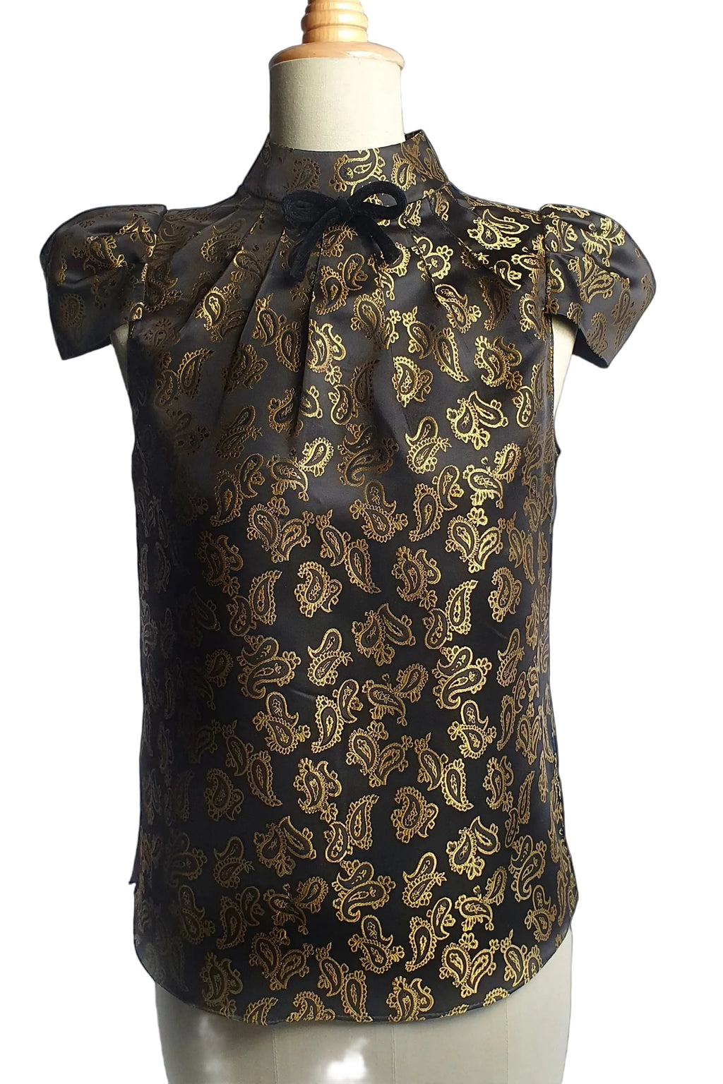 Black blouse with gold paisley pattern on a mannequin against a white background
