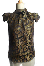 Black blouse with gold paisley pattern on a mannequin against a white background