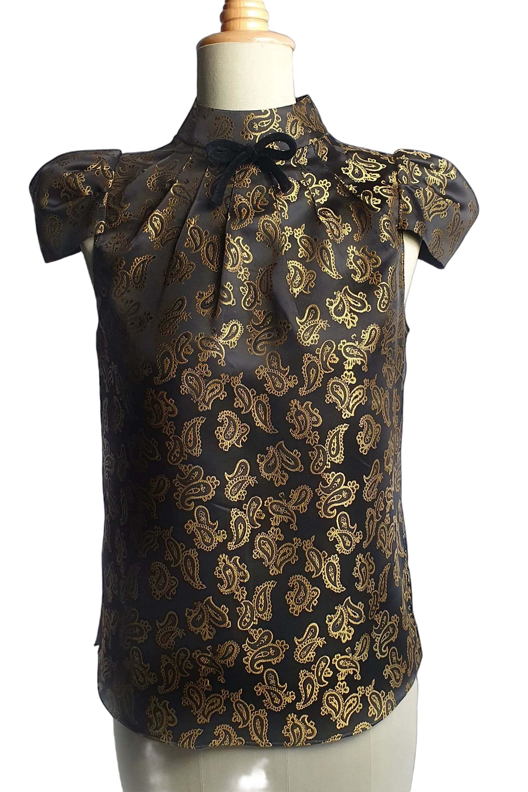 Black blouse with gold paisley pattern on a mannequin against a white background