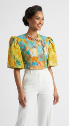 Woman wearing a colorful top and white pants on a white background