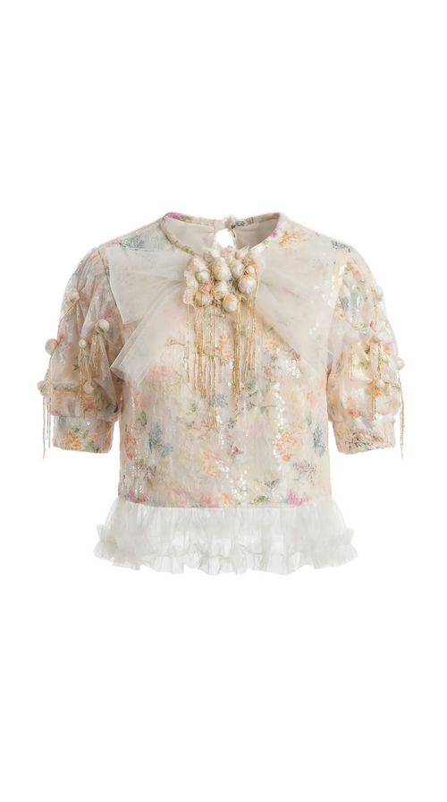 Sheer blouse with floral patterns and ruffled details on a white background