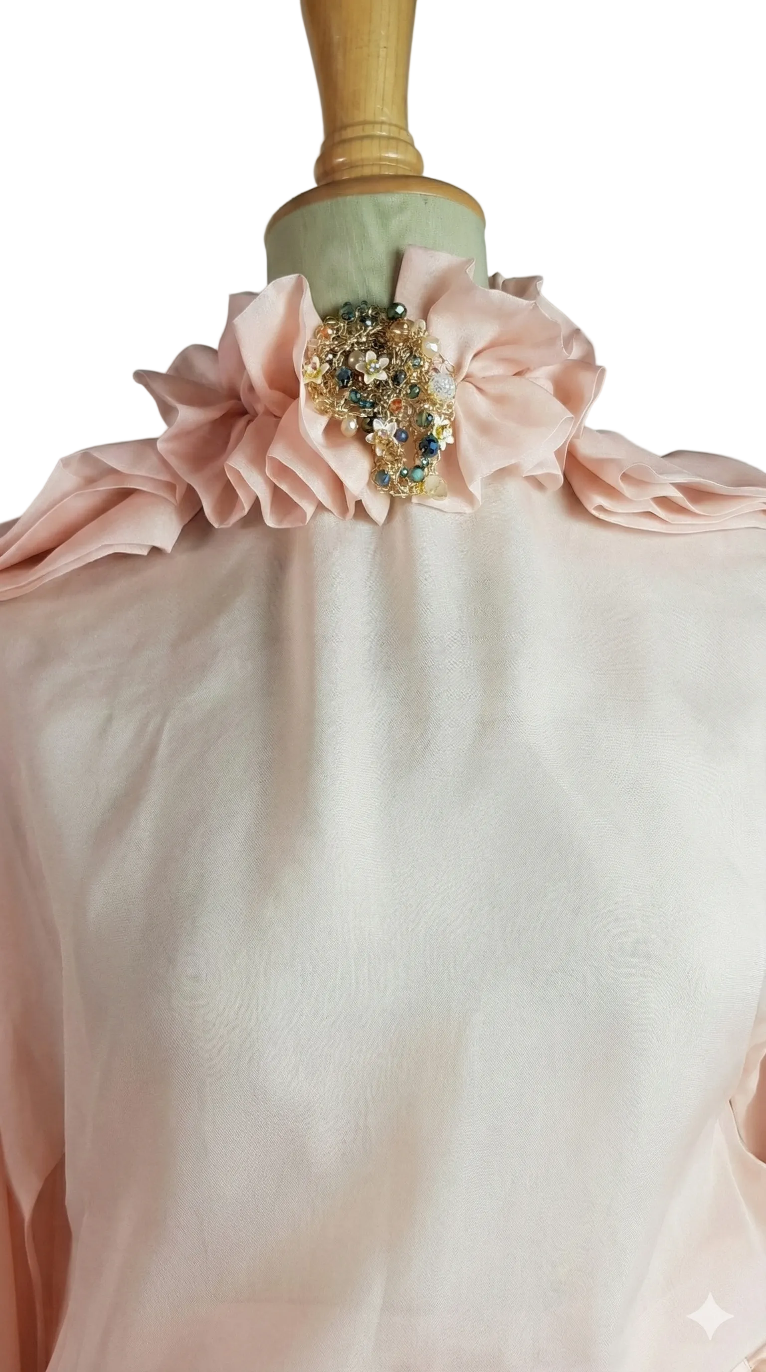 Close-up of a pink blouse with floral embellishments on a mannequin against a neutral background